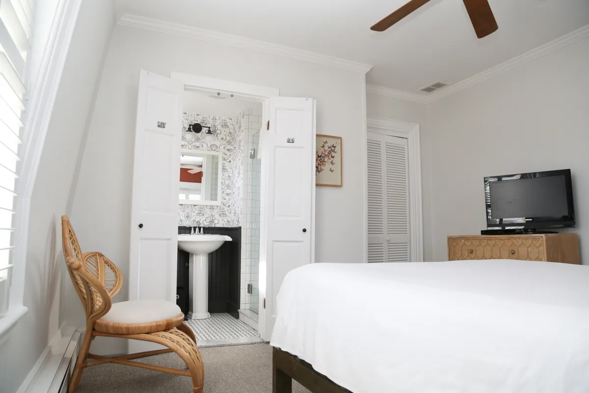 Bedroom with white standard queen bed and TV in the corner