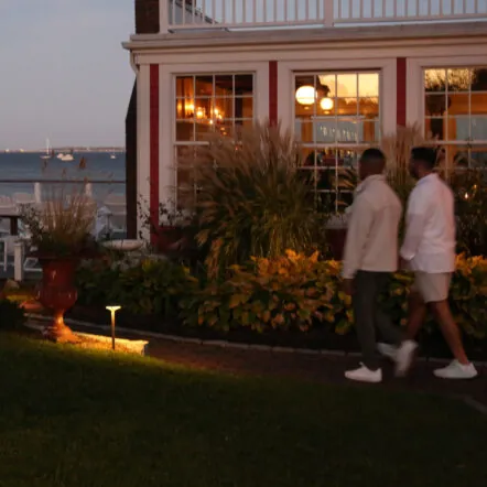 Two man walking past a house at susnset
